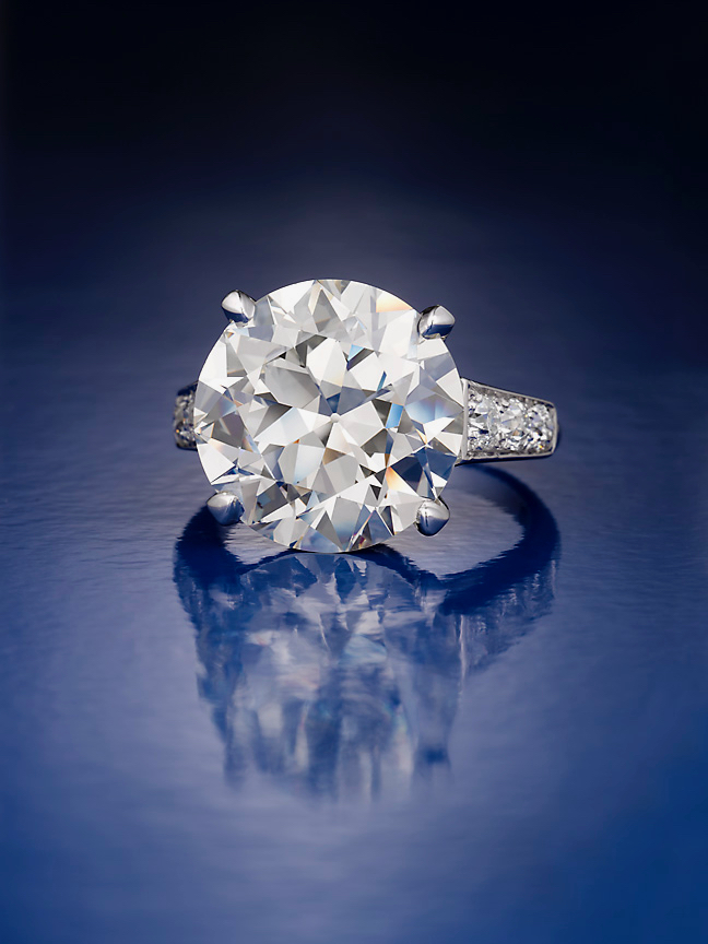 A diamond ring is shown on top of a blue surface.