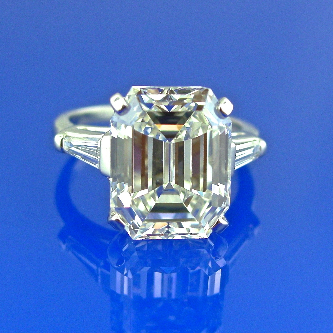 A diamond ring with three side stones on a blue background