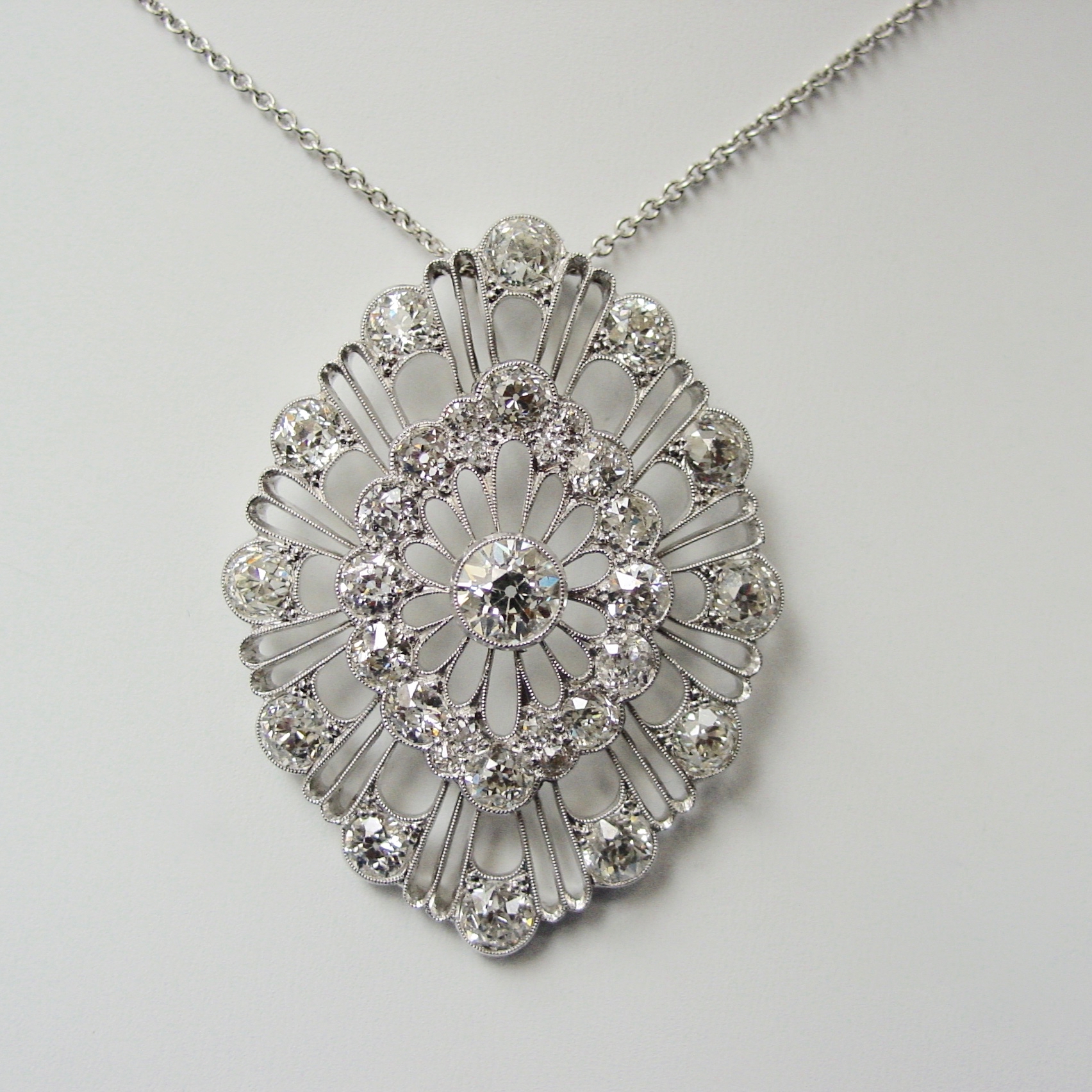 A silver necklace with a large pendant on it.