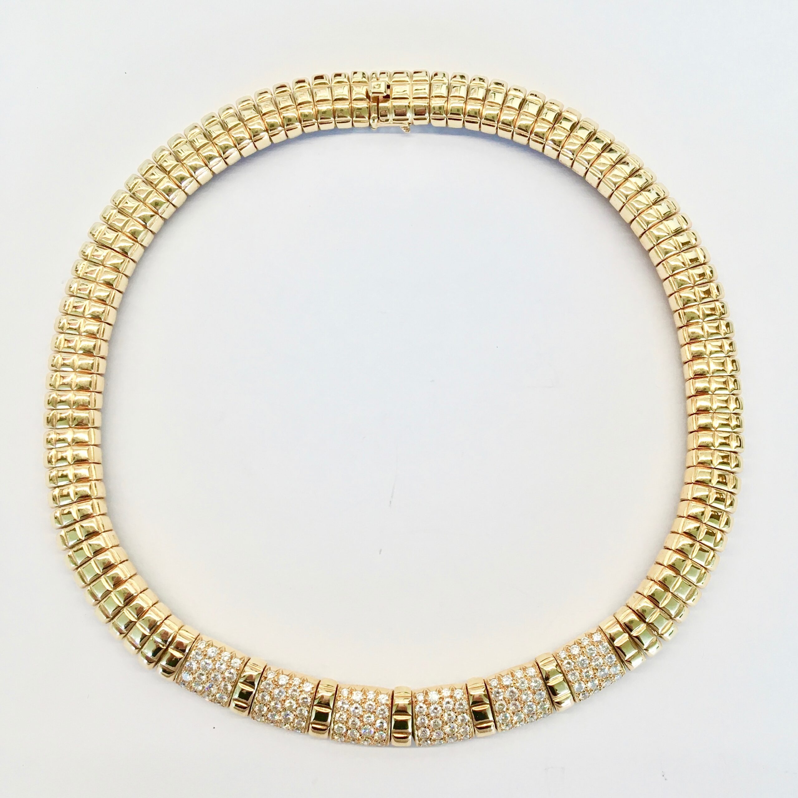 A gold necklace with white stones on it.