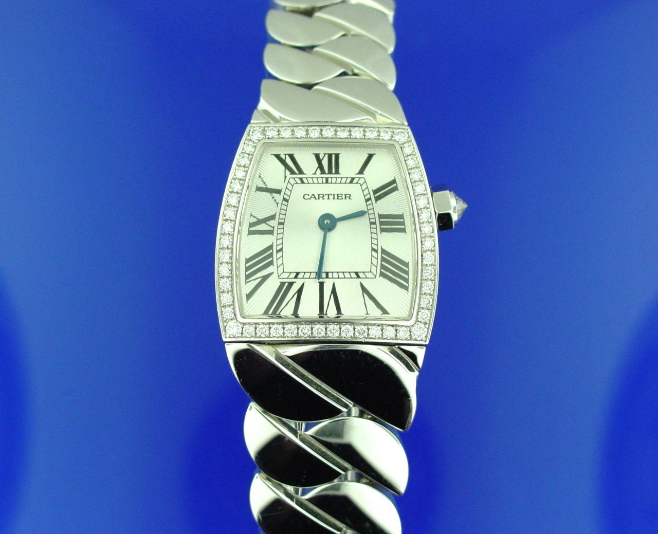 A silver watch with diamonds on the side of it.