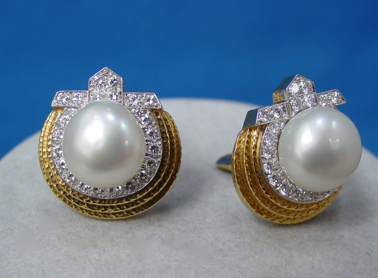 A pair of earrings with pearls and diamonds.