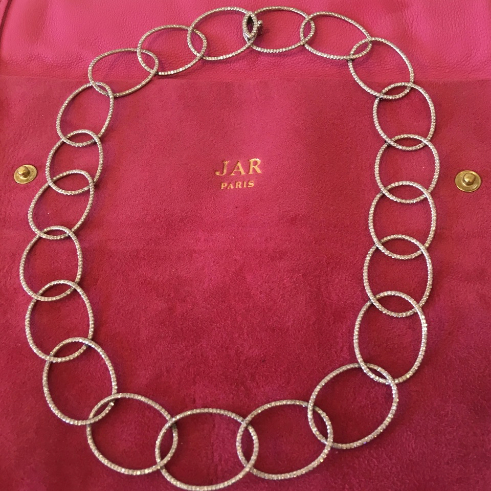 A necklace is shown on the red bag.