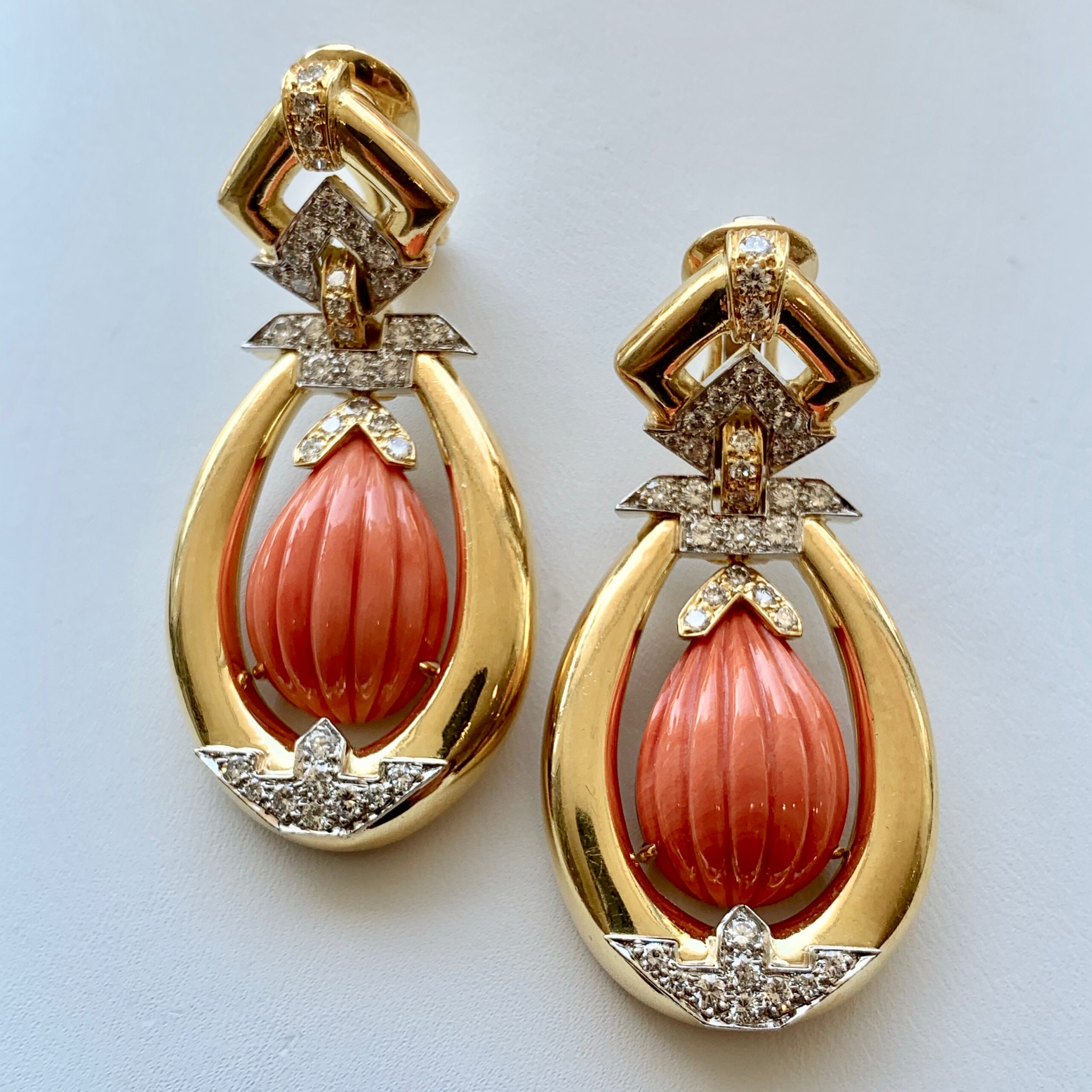 A pair of earrings with coral and diamonds.