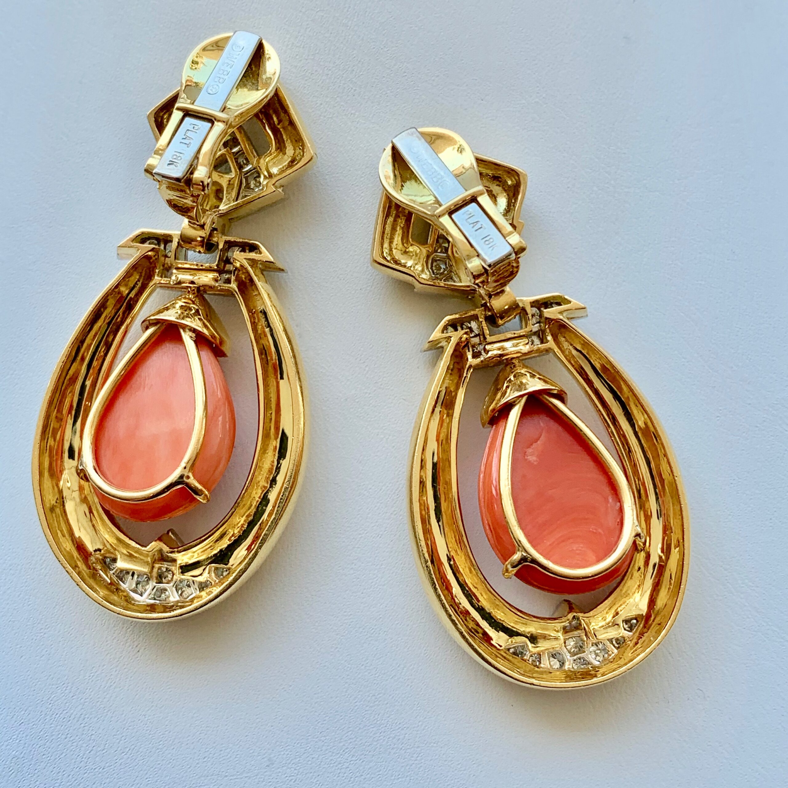 A pair of gold earrings with coral and diamond accents.
