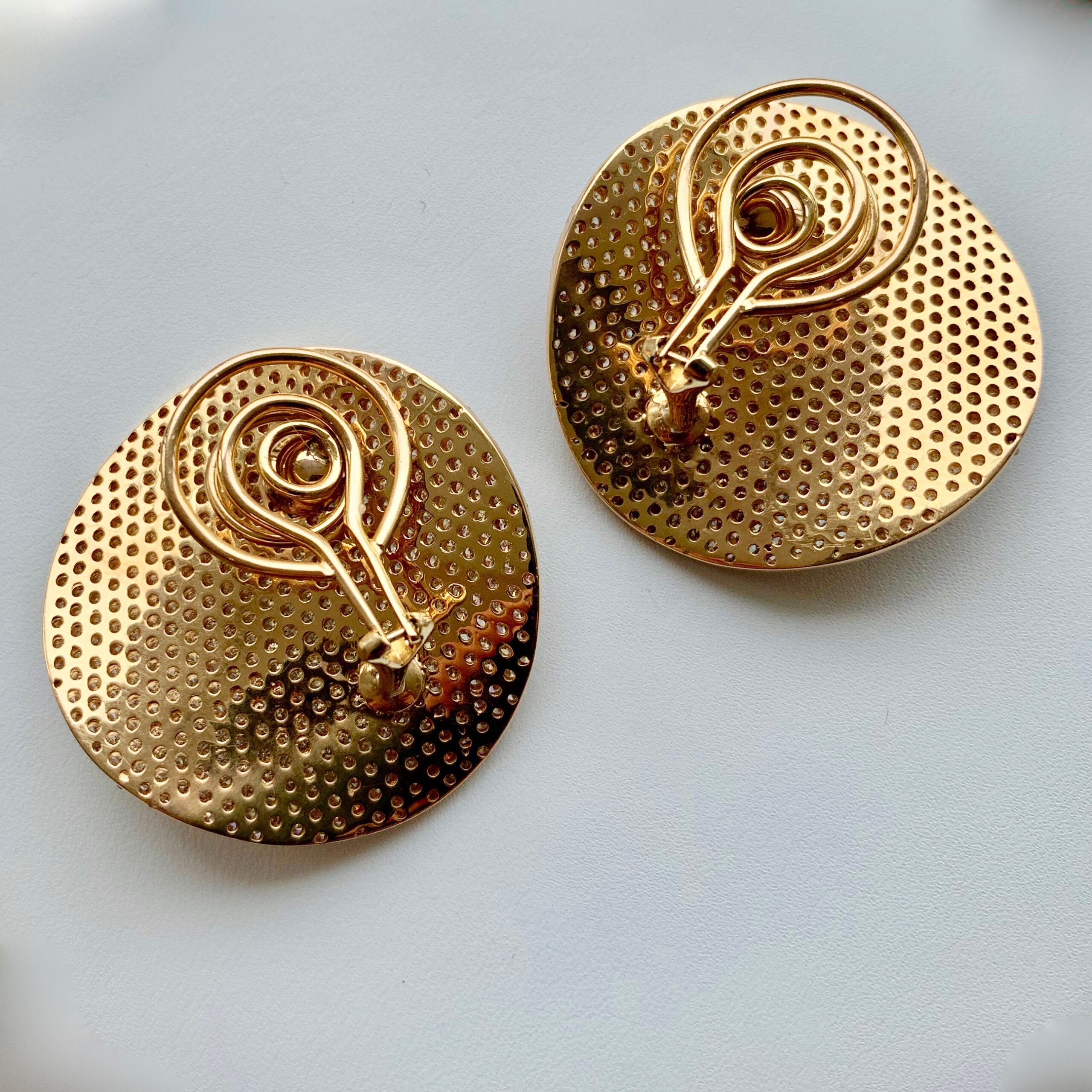 A pair of gold earrings with swirls on them.