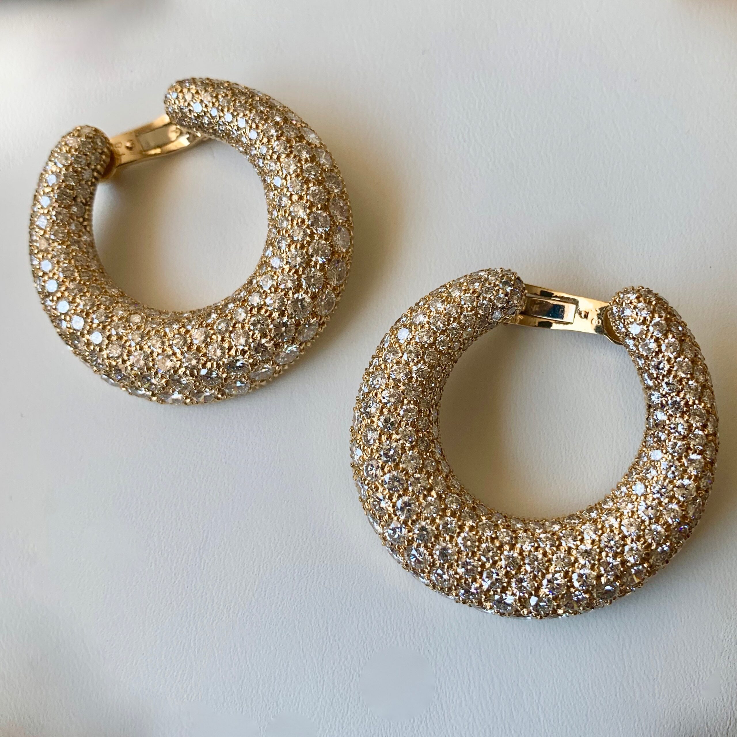 A pair of gold earrings with white stones.