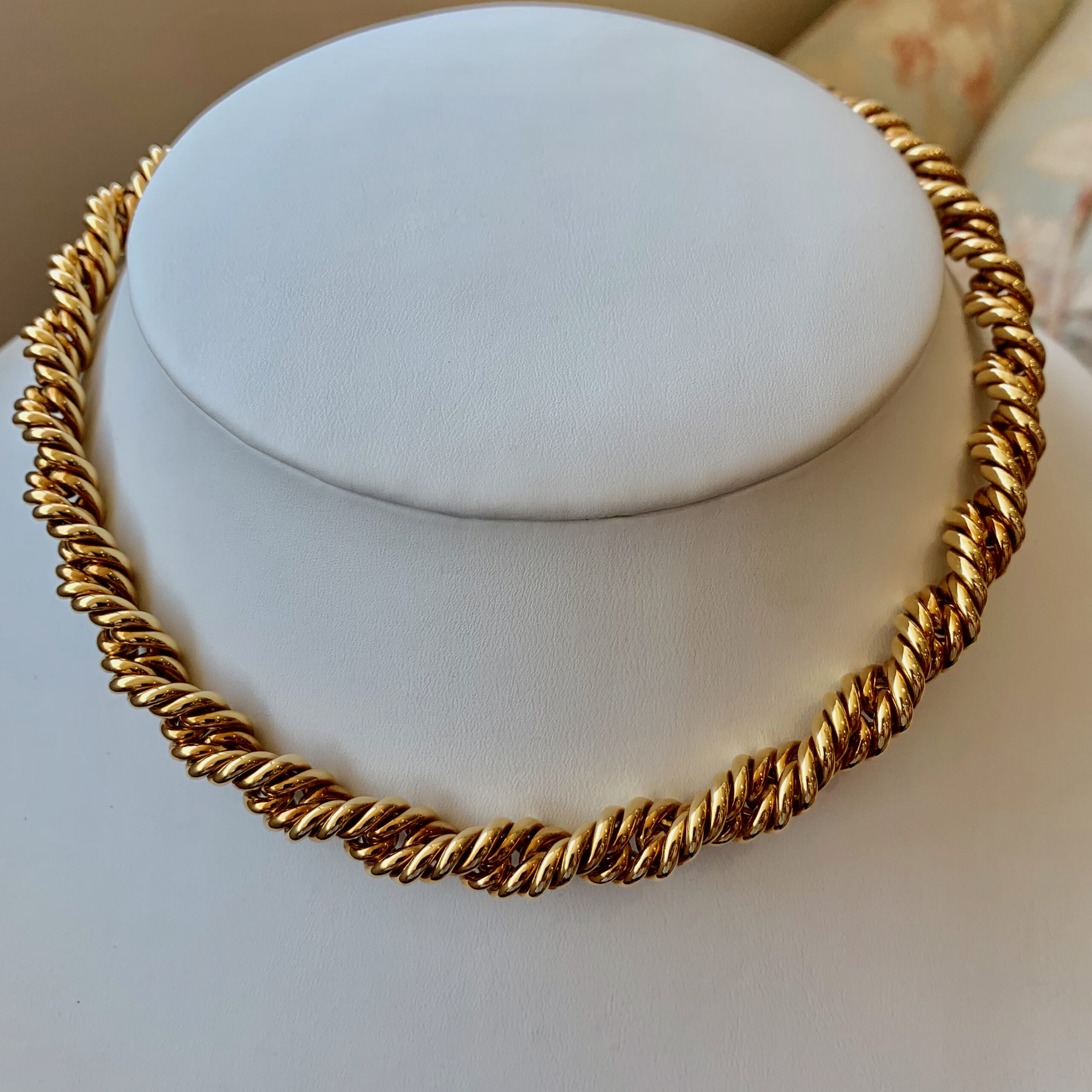 A gold necklace sitting on top of a white counter.
