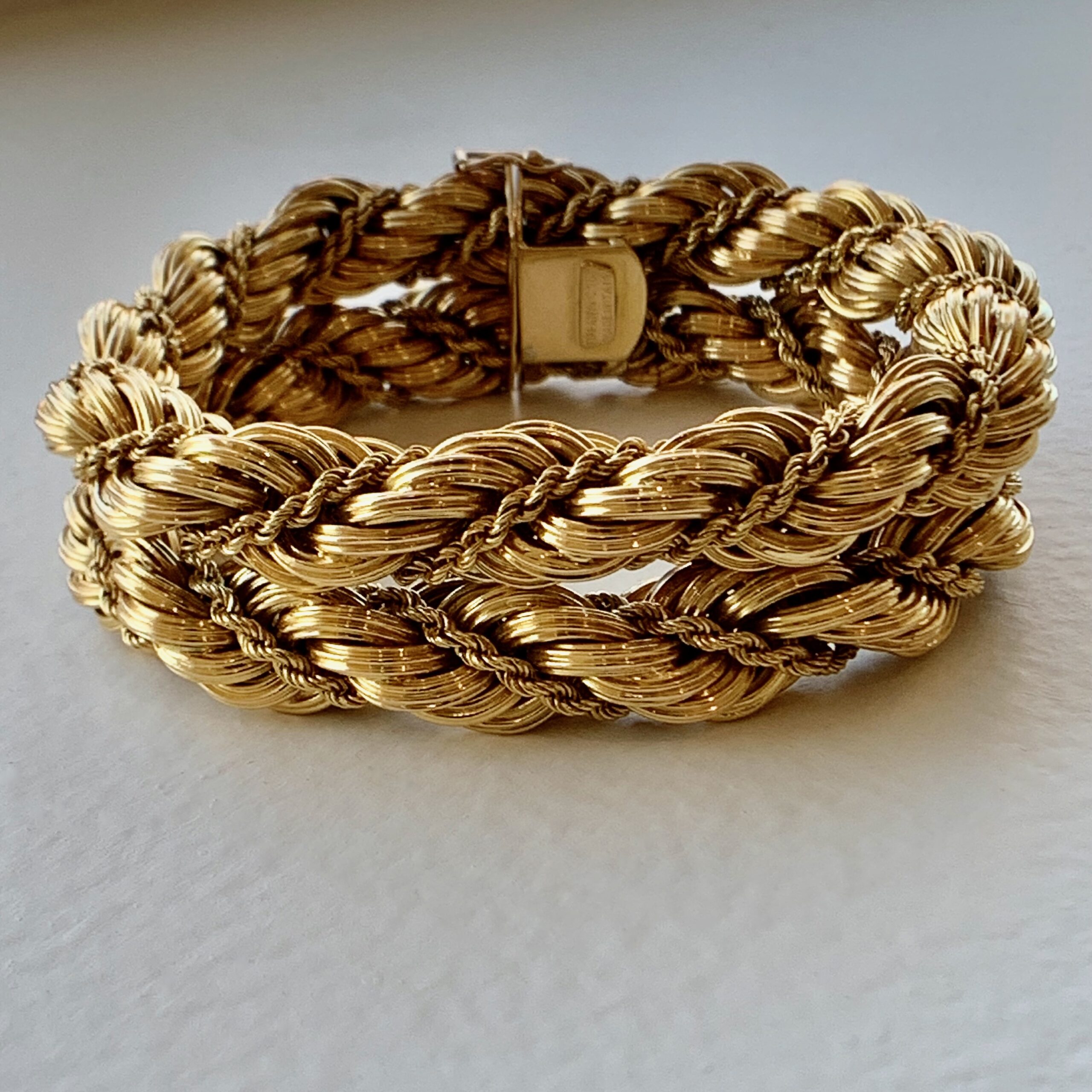 A gold bracelet is shown on top of a table.