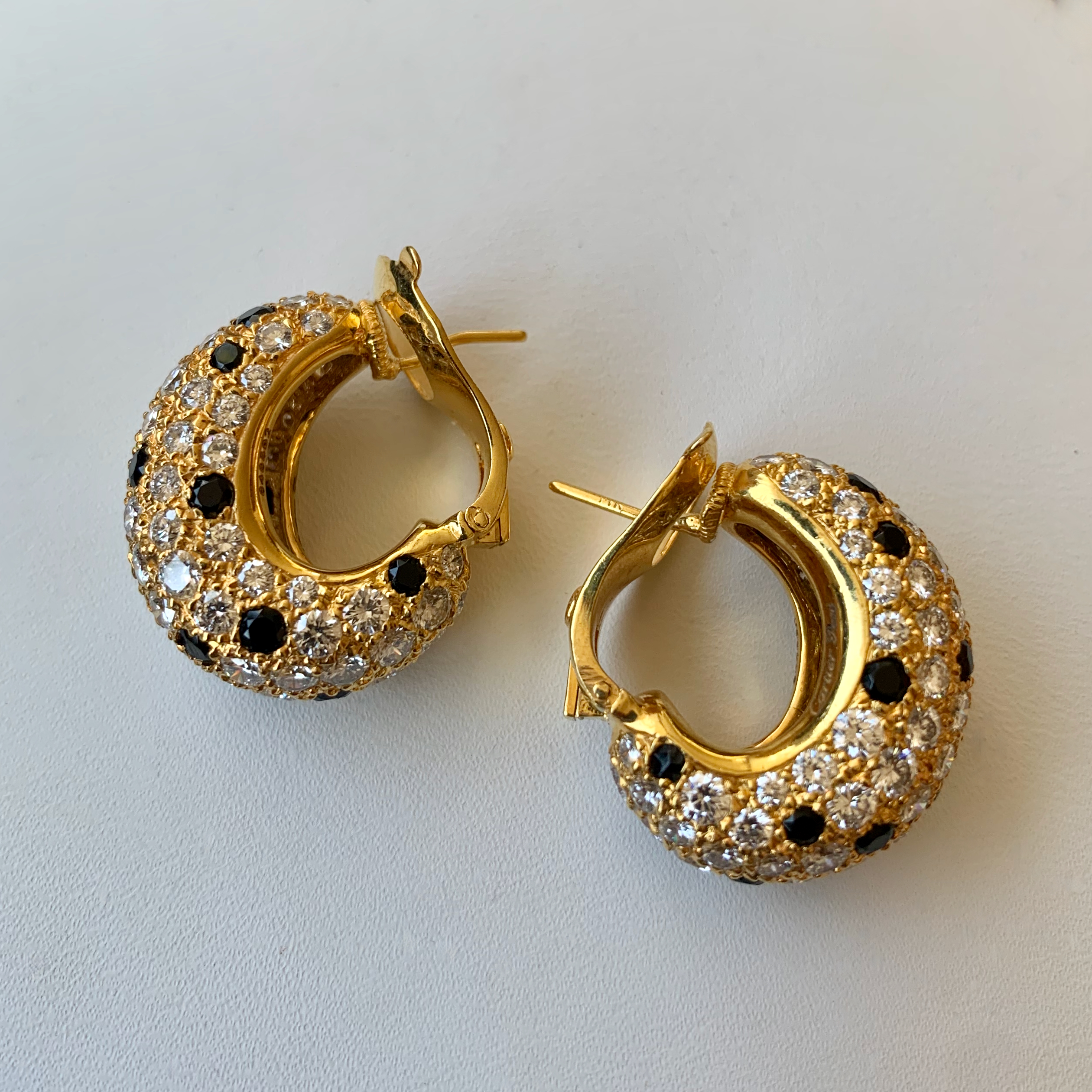 A pair of gold earrings with black and white diamonds.
