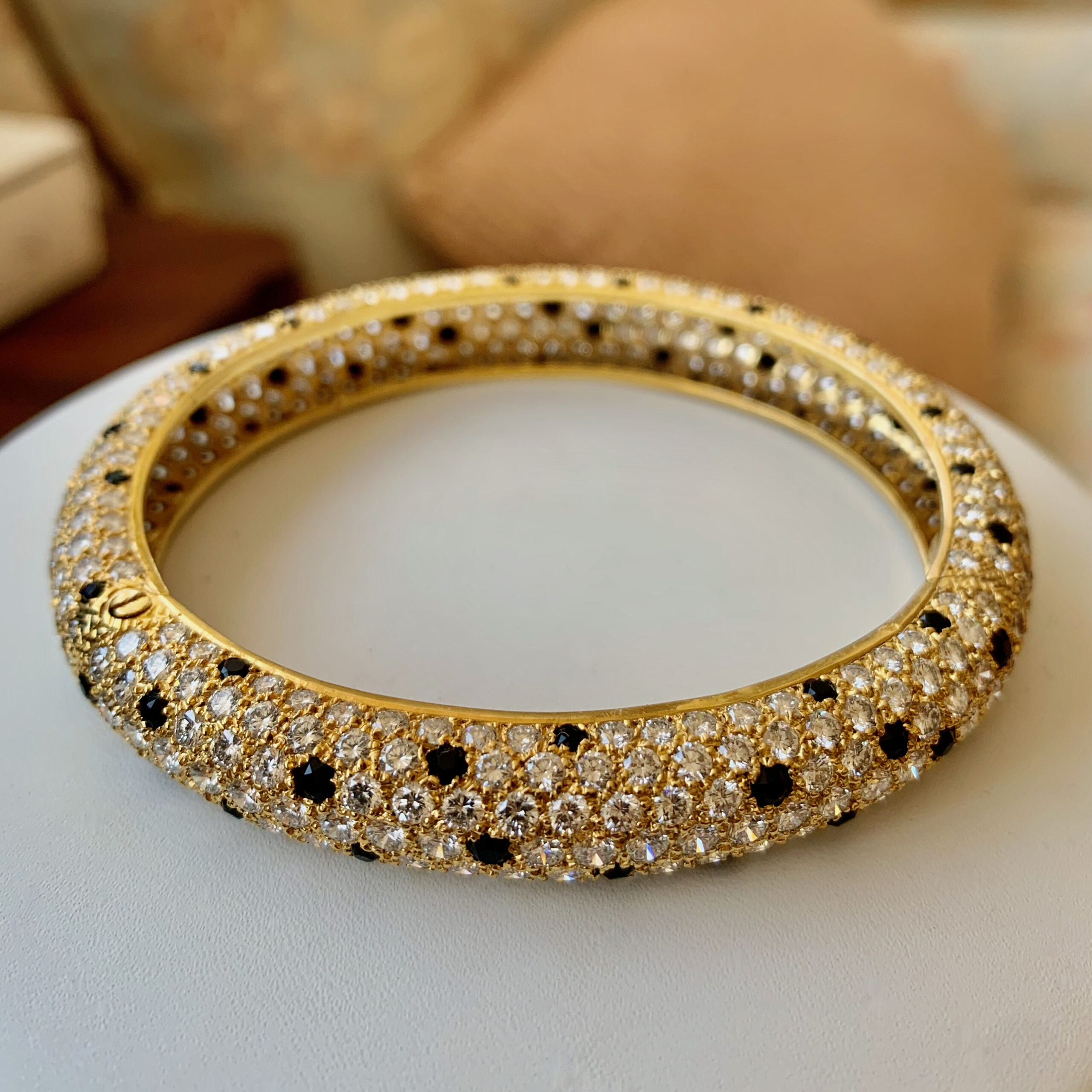 A gold and black bracelet sitting on top of a table.