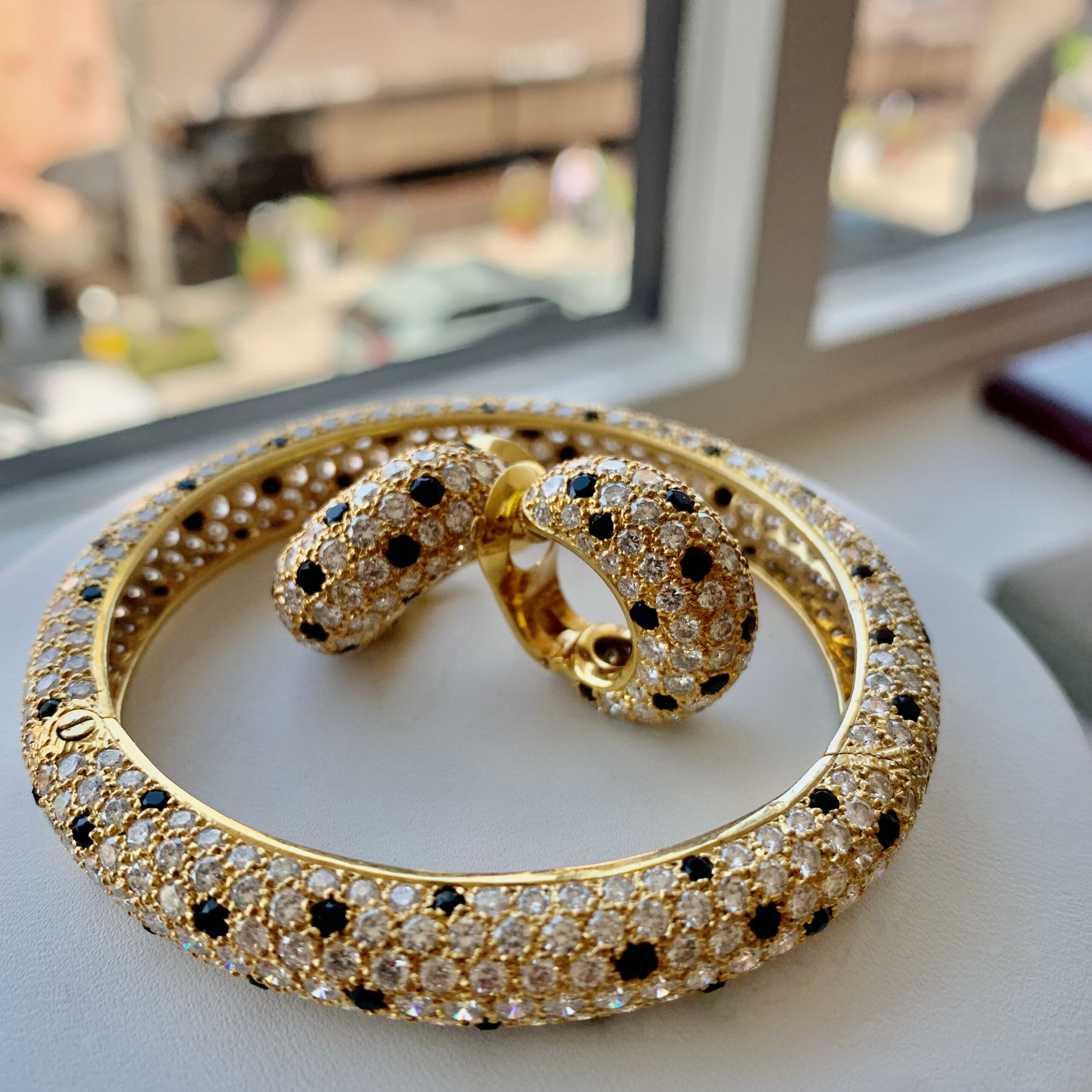 A gold bracelet and earrings set on top of a table.