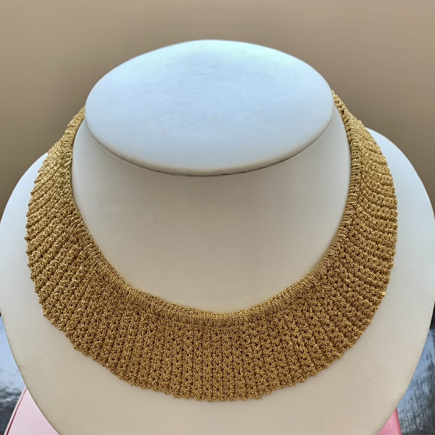 A gold necklace is displayed on a white display.