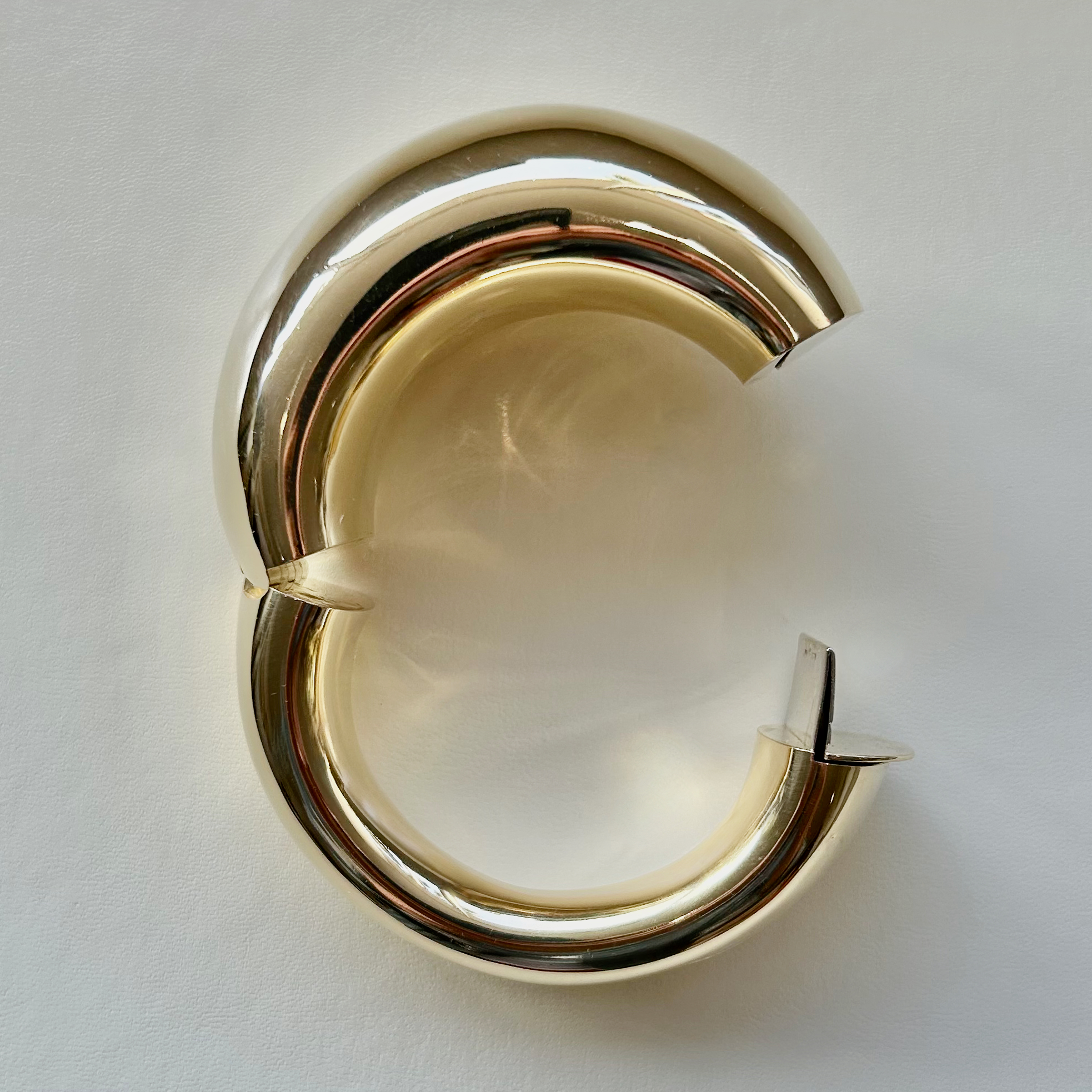 A pair of gold earrings sitting on top of a table.